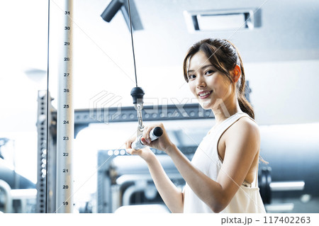 スポーツジムでトレーニングする若い女性 カメラ目線 笑顔 スポーツジムでトレーニングする若い女性 カメラ目線 笑顔 117402263