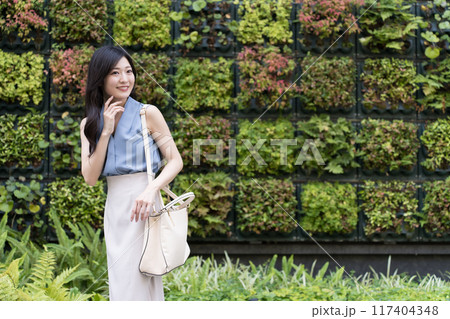 壁面緑化されたビルの前で振り向くビジネスウーマン 117404348