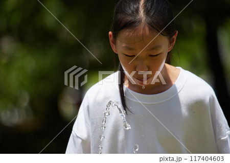 夏休みの公園で楽しく水遊びする小学生の女の子の様子 117404603
