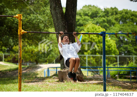 真夏の公園で鉄棒を遊んでいる小学生の女の子の様子 117404637