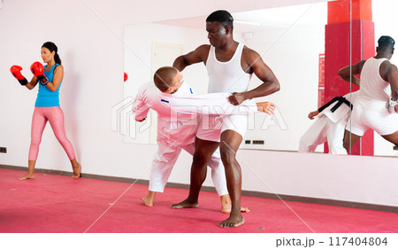 Men perform strength techniques and grabs at self-defense training in sports club Men perform strength techniques and grabs at self-defense training in sports club 117404804
