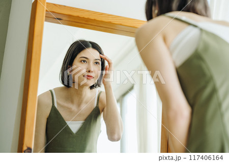 鏡を見て身支度する女性 117406164