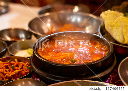 Kimchi Soup served in a bowl, with Korean side dishes served on the table 117406535