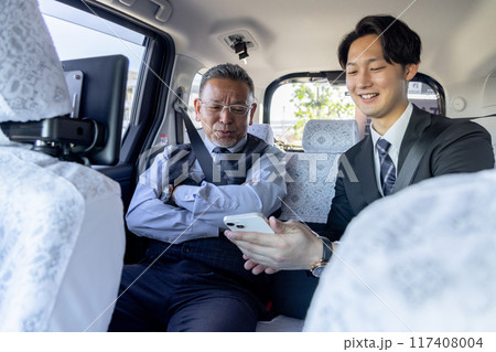 タクシーの後部座席で打合せをするビジネスマン 117408004