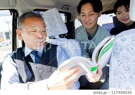 旅行先のタクシー内でガイドブックを見せて行き先を伝えるカップル 旅行先のタクシー内でガイドブックを見せて行き先を伝えるカップル 117408030