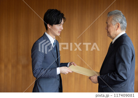 社外秘の封筒を渡すビジネスマン 社外秘の封筒を渡すビジネスマン 117409081