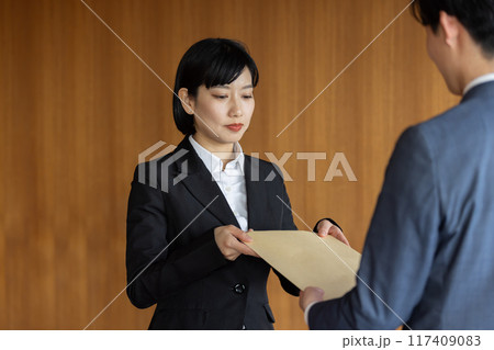 社外秘の封筒を渡すビジネスマン 社外秘の封筒を渡すビジネスマン 117409083
