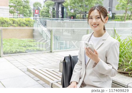 ベンチに座ってスマホで検索する若い女性 117409829