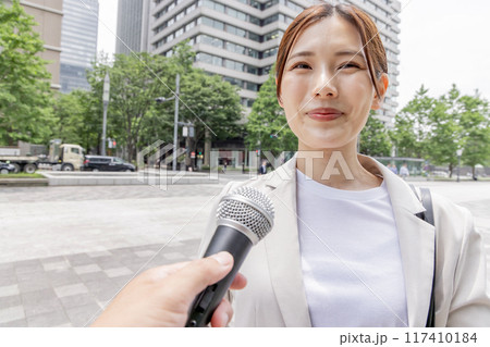インタビューを受けるビジネスウーマン（取材・マイク） 117410184