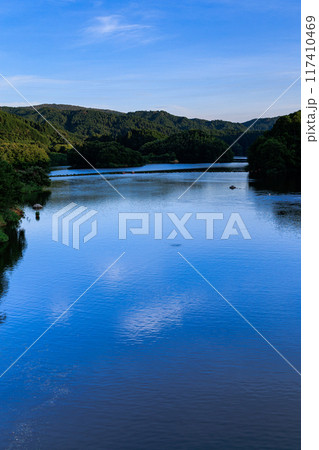 2024年夏奈良市東部布目ダムの夕景　南東側に広がるダム湖の水面と広大な青空　湖面に映る上空の薄雲 117410469