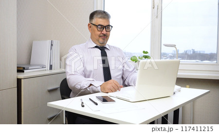 A man in a white shirt and tie works in the office 117411215