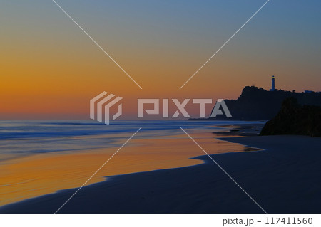暁色に染まる空を背景に薄磯海岸の砂浜に打ち寄せる波と塩屋崎灯台の風景　Ver3 117411560