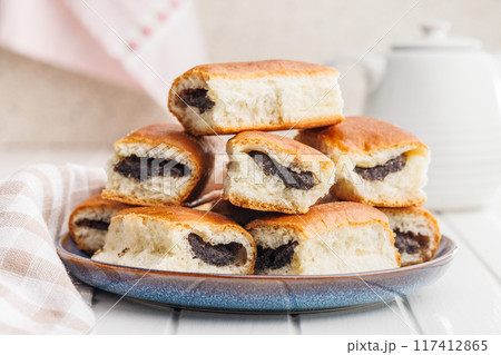 Sweet bun with poppy seed on plate on white table. Sweet bun with poppy seed on plate on white table. 117412865