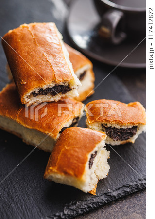 Sweet bun with poppy seed on black table. 117412872