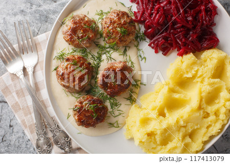 Tender meatballs served in a rich, creamy gravy with mashed potatoes and beet salad close-up in a plate. Horizontal top view Tender meatballs served in a rich, creamy gravy with mashed potatoes and beet salad close-up in a plate. Horizontal top view 117413079