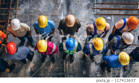 Top view of workers wearing colorful safety helmets are line up to get information before work at a construction site background. AI generated. 117413637