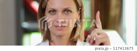 Woman doctor pointing finger up in medical office Woman doctor pointing finger up in medical office 117413675