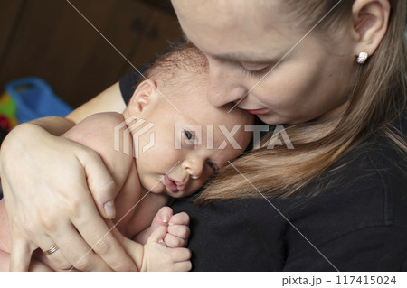 The newborn girl clung to her mother. Young woman with a baby. The newborn girl clung to her mother. Young woman with a baby. 117415024