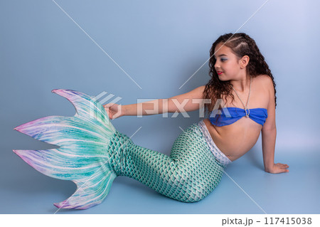 A beautiful girl in a mermaid costume isolated on light-blue background A beautiful girl in a mermaid costume isolated on light-blue background 117415038