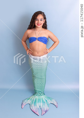 Beautiful smiling girl in a mermaid costume, standing on a blue background 117415040