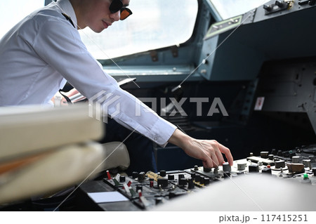 Cropped shot of male pilot preparing for takeoff, adjusting switches in the airplane cockpit Cropped shot of male pilot preparing for takeoff, adjusting switches in the airplane cockpit 117415251