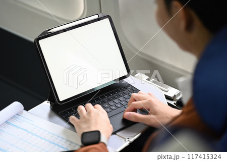 Close up shot businessman using digital tablet and working with documents during flight 117415324