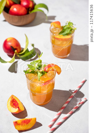 Two glasses with refreshing peach tea with ice and mint. Homemade cold summer drink Two glasses with refreshing peach tea with ice and mint. Homemade cold summer drink 117415636