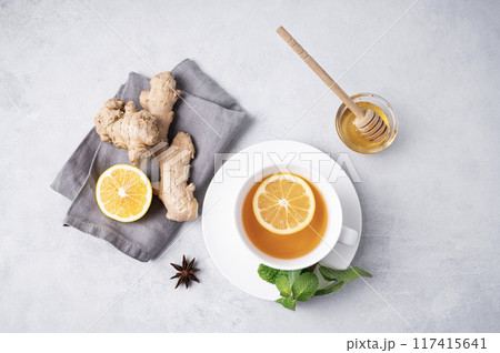A cup of tea with lemon, honey, mint and ginger on a light background. A cup of tea with lemon, honey, mint and ginger on a light background. 117415641