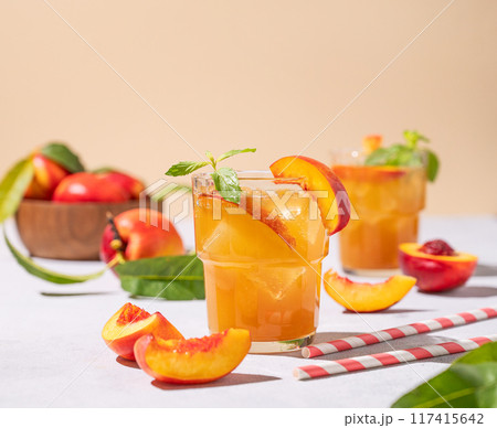 Two glasses with peach tea with ice and mint. Vegetarian and healthy homemade cold drink  117415642