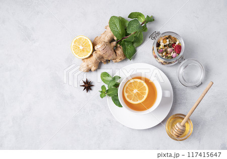 A cup of tea with lemon, honey, mint and ginger on a light background.  117415647