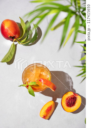 Refreshing peach tea with ice and mint. Homemade cold healthy drink on a light background  117415650