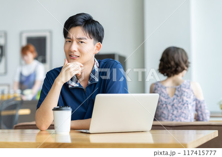 カフェでパソコンを見る若い男性 117415777