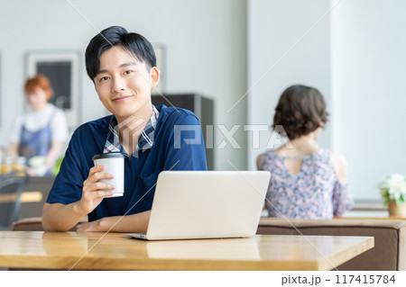 カフェでパソコンを見る若い男性 117415784