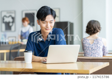 カフェでパソコンを見る若い男性 117415786