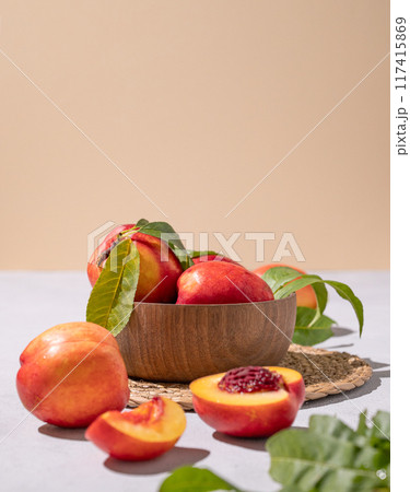 Juicy and sweet nectarines in a bowl on a light background with shadow. Healthy organic farm fruit 117415869