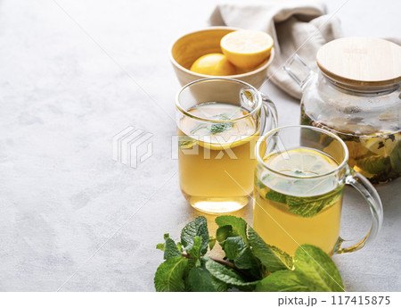 Two glasses of tea with fresh lemon, honey, mint and ginger on a light background Two glasses of tea with fresh lemon, honey, mint and ginger on a light background 117415875