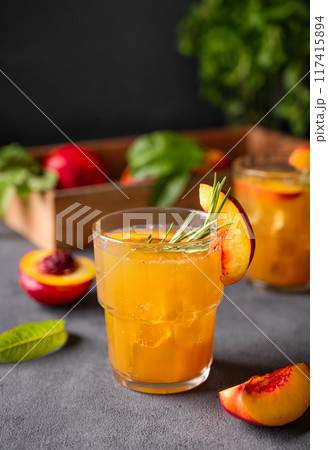 Peach tea with ice and rosemary on a glass. Vegan homemade healthy  drink on a dark background 117415894