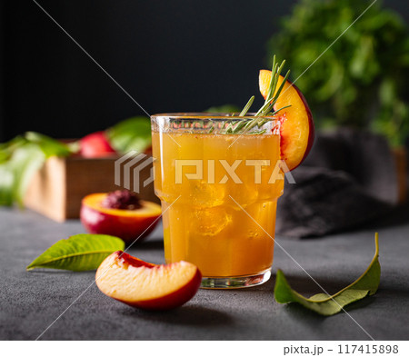 Peach tea with ice and rosemary on a glass. Vegan homemade healthy  drink on a dark background  117415898