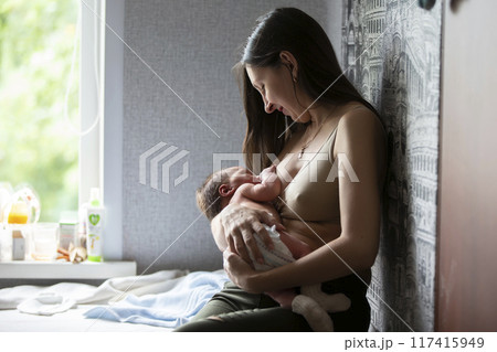 The woman is breastfeeding the baby. Breast-feeding. 117415949