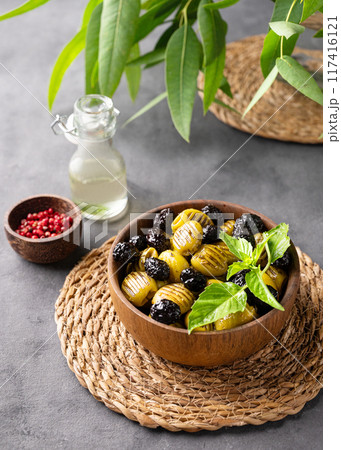 A set of green and black dried olives in bowl on a dark background with olive oil and eucalyptus A set of green and black dried olives in bowl on a dark background with olive oil and eucalyptus 117416121