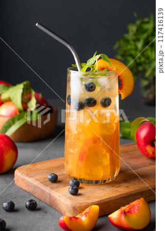 Peach tea with ice, mint and blueberry on tall glass. Vegan homemade cold healthy drink 117416139