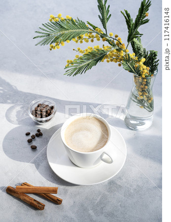 Cappuccino or latte with milk foam in a white cup on a light blue background with coffee beans  117416148