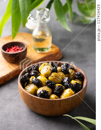 A set of green and black dried olives in bowl on a dark background with olive oil and eucalyptus  117416429
