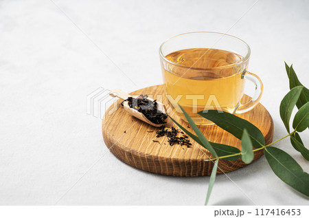 Fragrant herbal tea in a glass cup on a cutting board on a white background with eucalyptus branches 117416453
