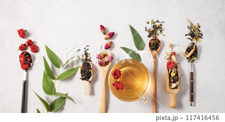 Flat lay herbal tea with pomegranate flowers and eucalyptus leaves in a wooden spoon and cup of tea 117416456
