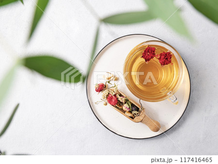 Herbal tea with pomegranate flowers in a glass cup on a plate on a white background with eucalyptus  117416465