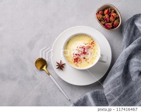 Golden milk latte with turmeric and rose petals. Trendy Indian drink Moon milk with natural spices. 117416467