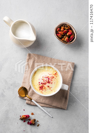 Flat lay of a golden milk latte with turmeric and rose petals. Trendy Indian drink Moon milk  Flat lay of a golden milk latte with turmeric and rose petals. Trendy Indian drink Moon milk  117416470