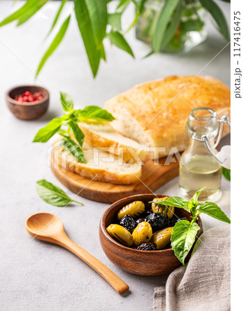 A set of green and black dried olives in wooden bowl  with fresh chiabatta bread 117416475
