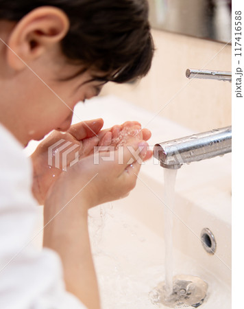 A boy washing his face under running tap A boy washing his face under running tap 117416588